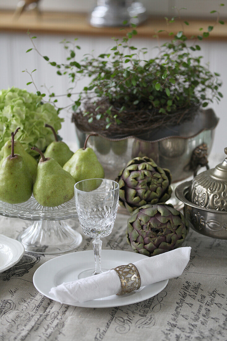 Table decoration with artichokes, pears, wire vine and hydrangea flower