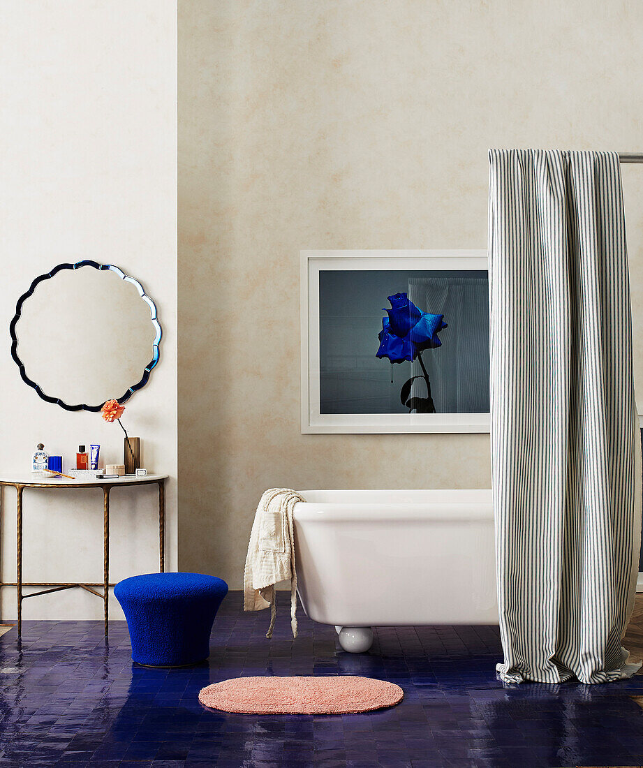 Shower curtain in front of free-standing bathtub in bathroom with blue-painted floor