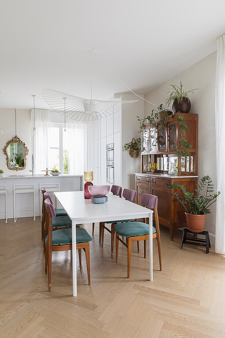 Weißer Tisch mit gepolsterten Stühlen und antike Anrichte in renovierter Wohnküche