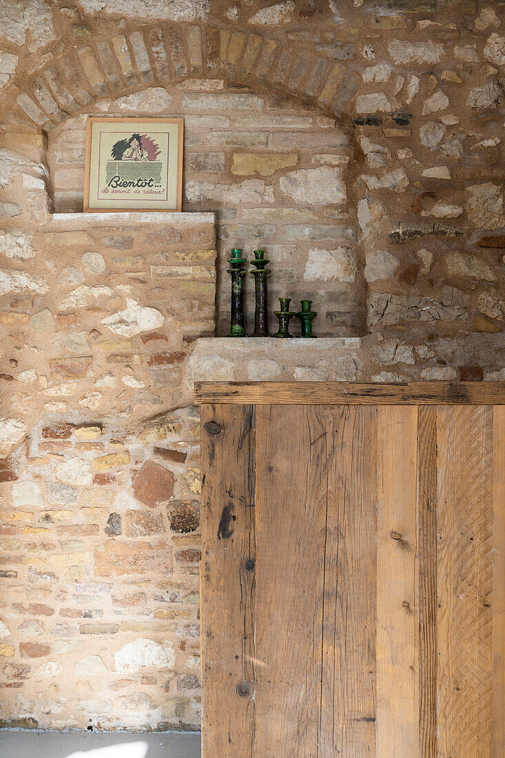 Küche mit Natursteinwand, davor halbhohe Holzwand als Raumteiler