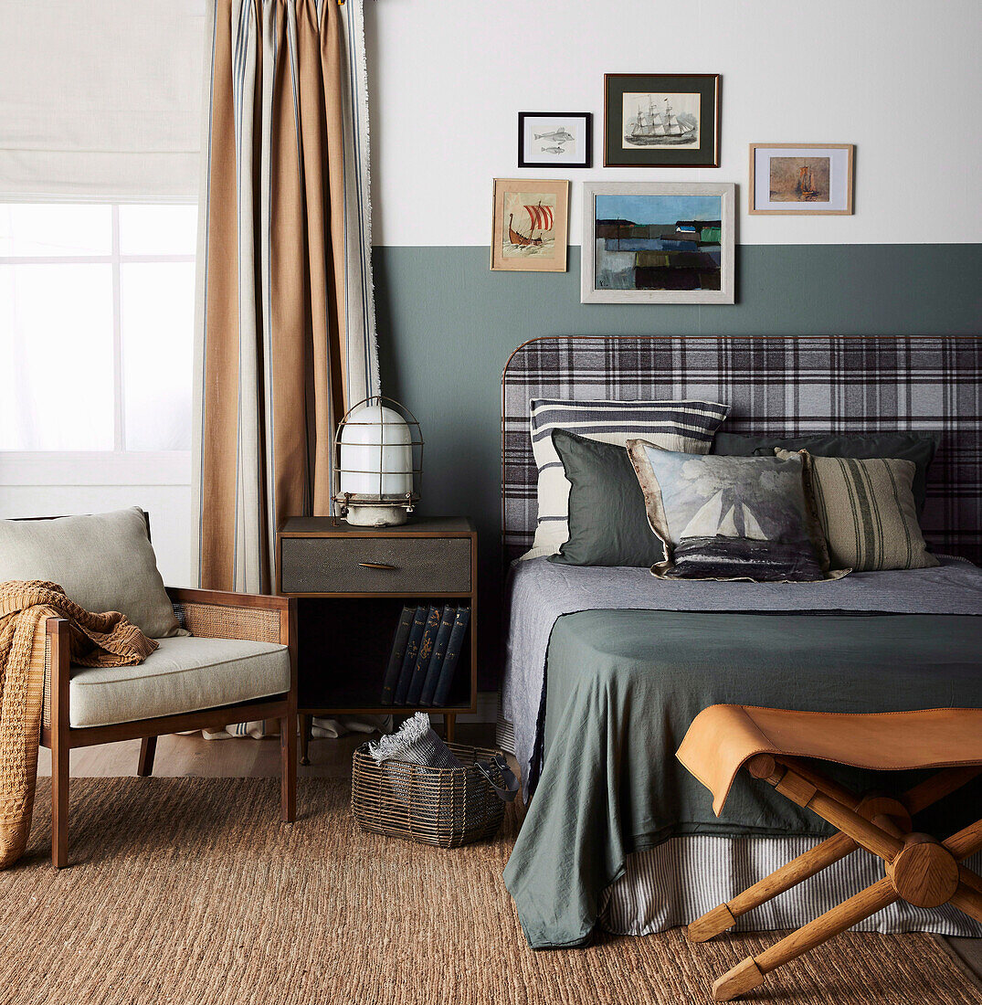Double bed with a flannel headboard, bedside table, armchair, and leather stool in bedroom
