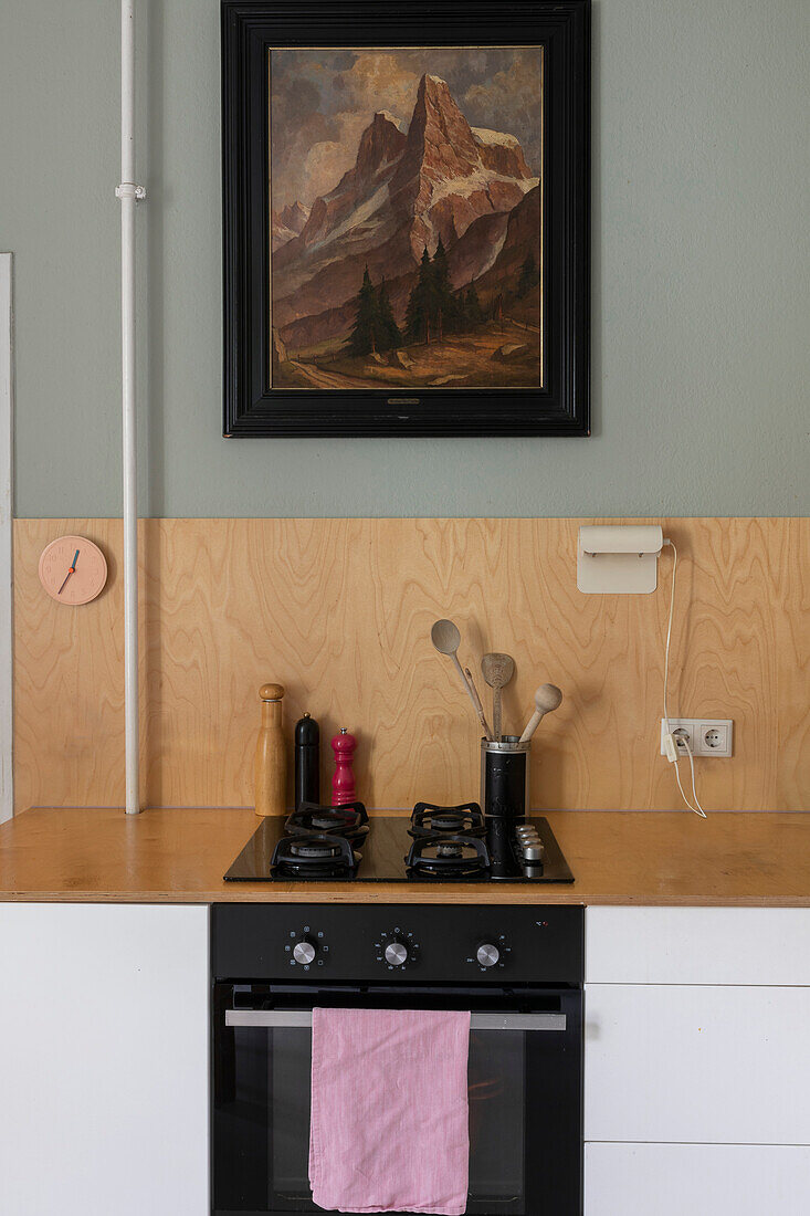 Küchenzeile mit Gasherd, darüber Holzpaneel und Vintage Gemälde