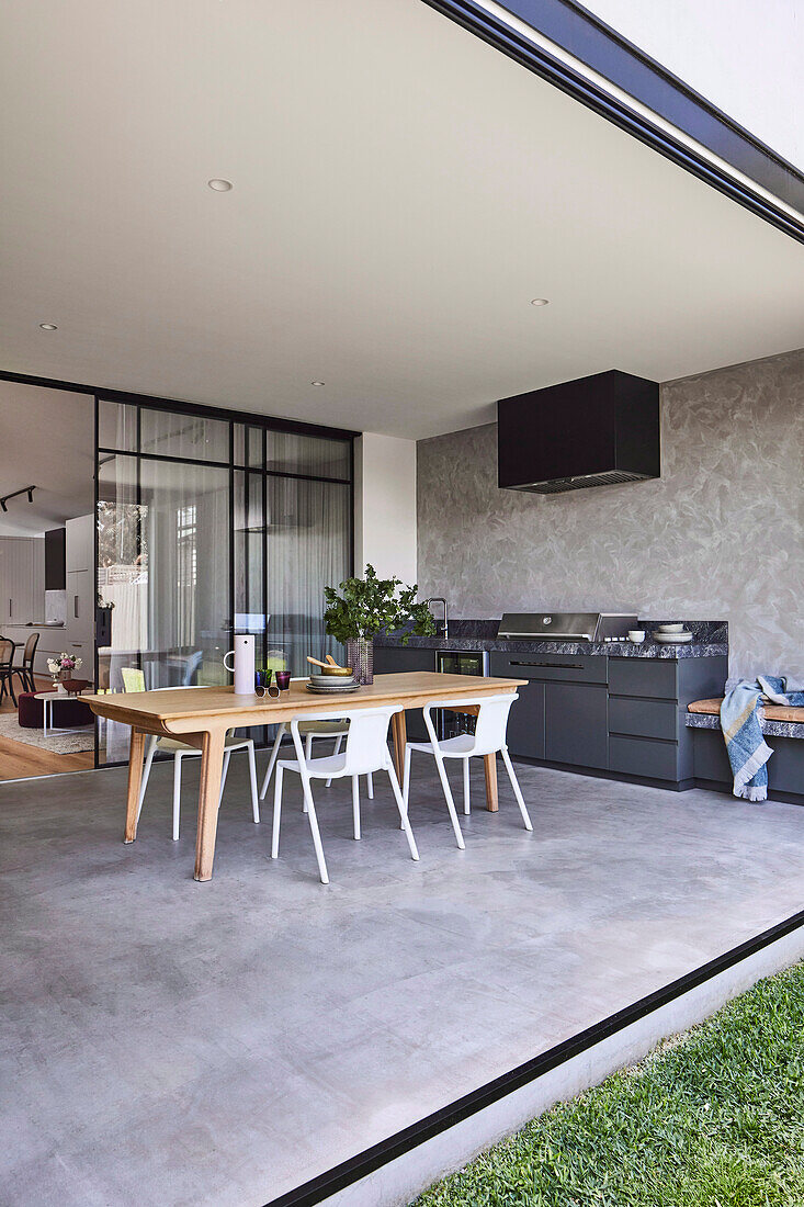 Überdachte Terrasse mit Esstisch, Stühlen und Outdoor-Küche mit Marmorplatte