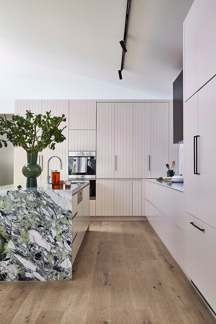 Einbauküche mit ausklappbaren Türen und Kücheninsel mit grüner Marmorverkleidung