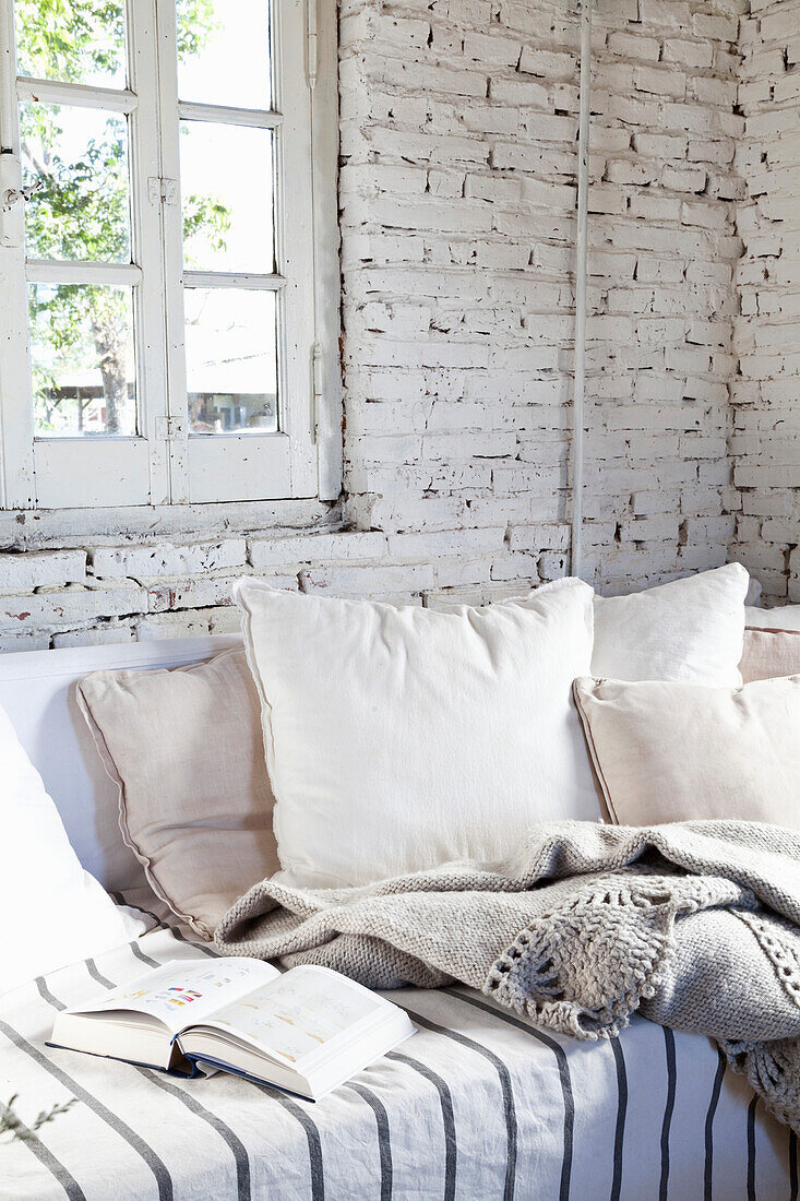 Sofa mit Kissen im Zimmer mit weiß getünchter Ziegelwand