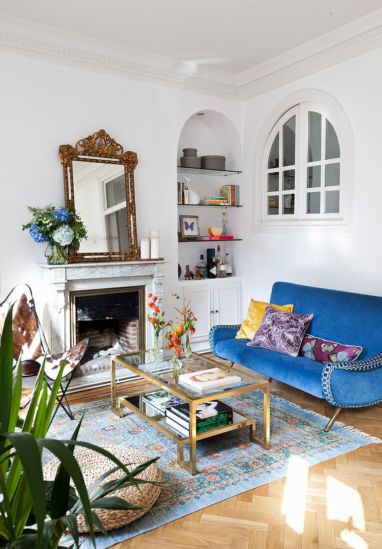 White living room with colorful accessories in a mix of styles, shelves in wall niche with round arch