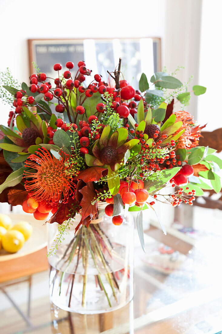 Bunter Blumenstrauß mit Protea in Glasvase auf Esstisch