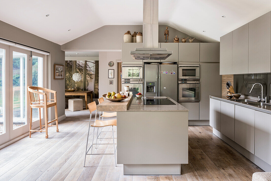 A fitted kitchen without handles, a kitchen island with a Corian worktop and a breakfast bar