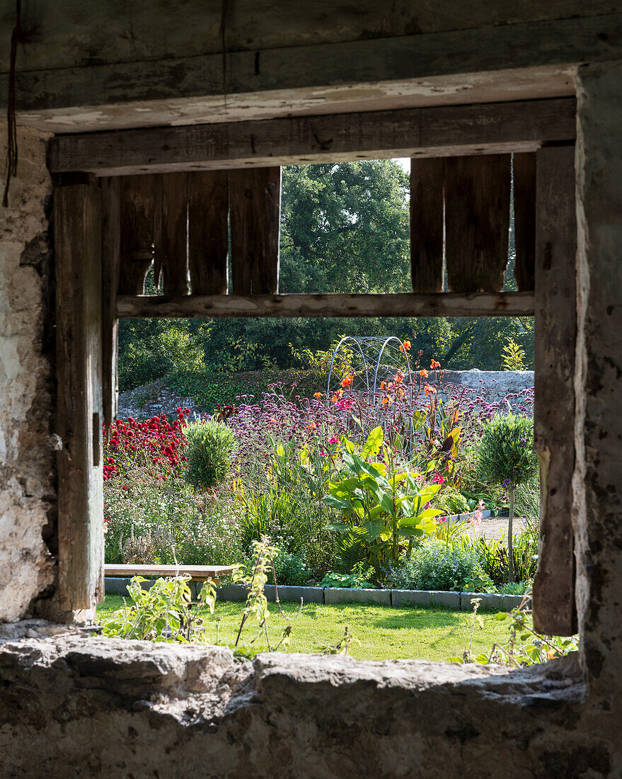 Blick durch rustikales Scheunenfenster auf den Garten