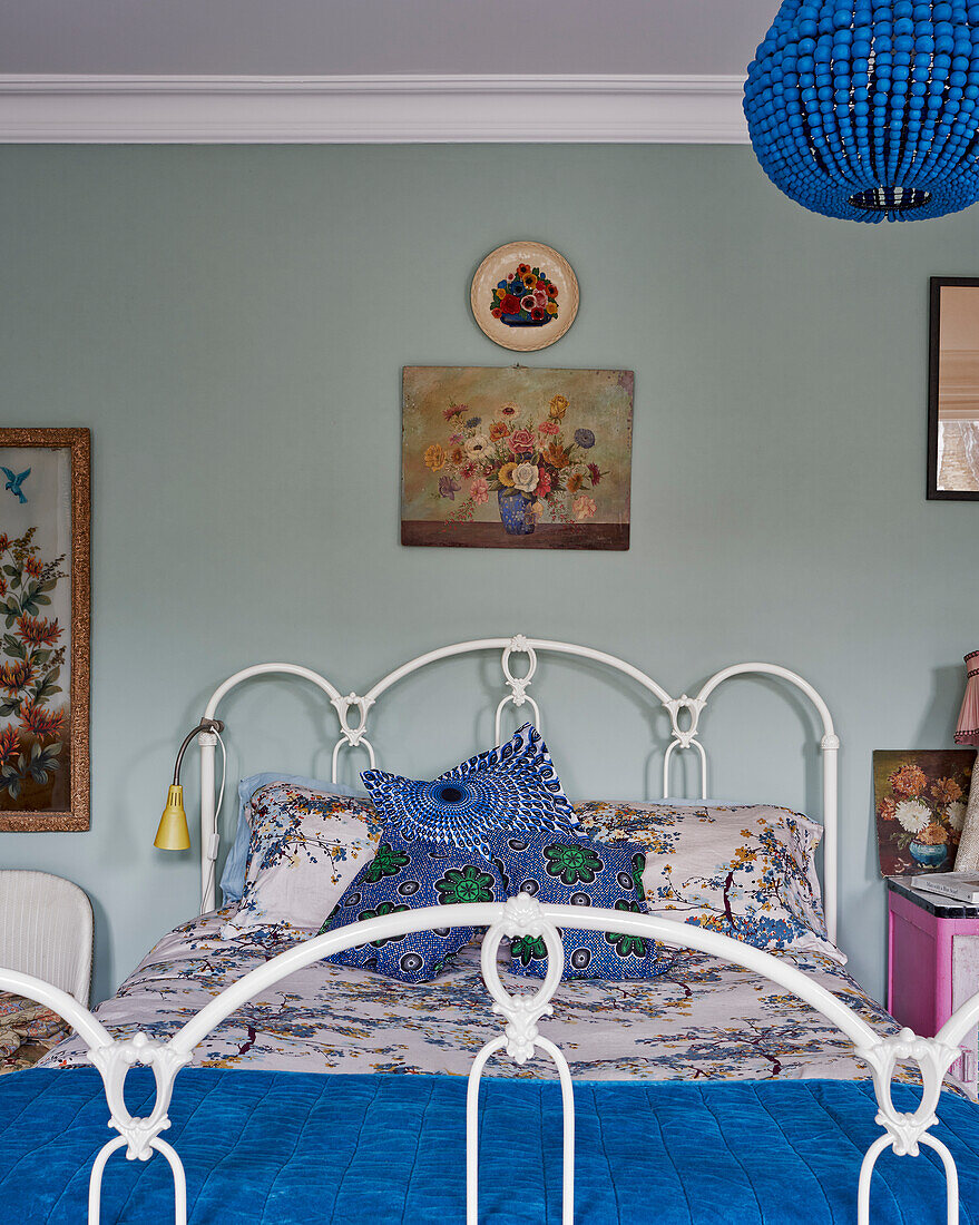 Blue beaded chandelier in bedroom with wrought iron bed