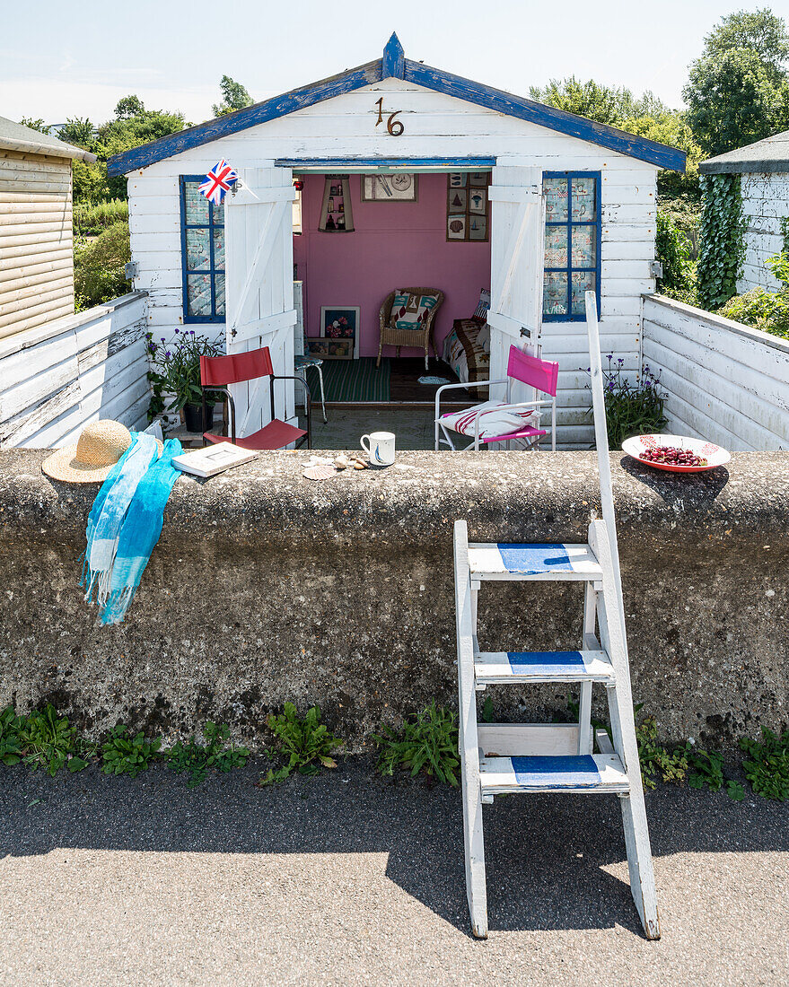 A view of a beach hut over a stone wall