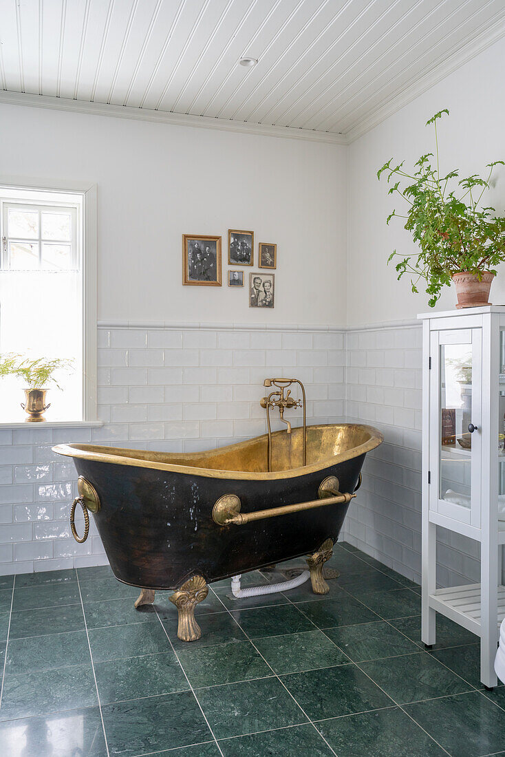 Freistehende Badewanne in Messing im Badezimmer mit grünen Bodenfliesen