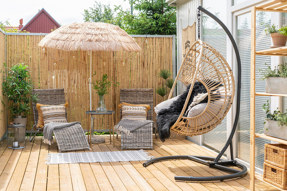 Wooden terrace with hanging chair and privacy screen