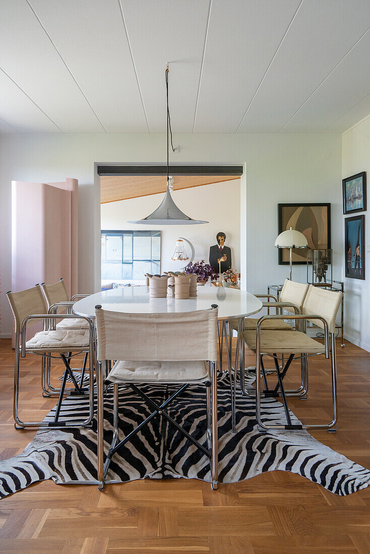 Ovaler Esstisch mit Klassikerstühlen auf Zebrafellteppich im Esszimmer