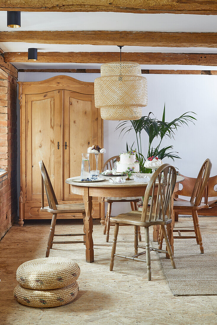 Rustic dining area with round table and wooden cupboard