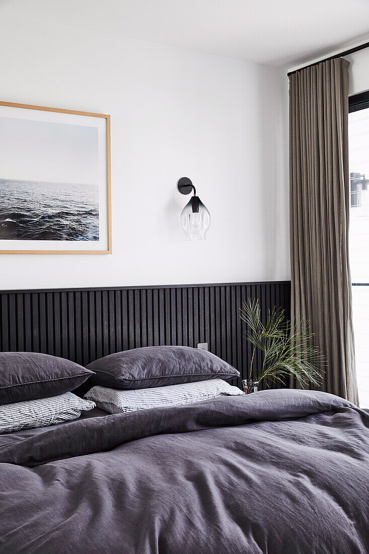 Doppelbett im Schlafzimmer mit schwarz gestrichener Holzverkleidung