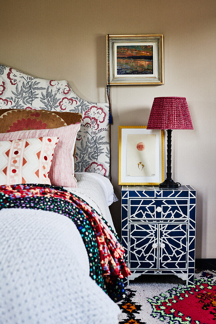 Blauer Nahcttisch mit Elfenbein-Intarsie neben Doppelbett im Schlafzimmer