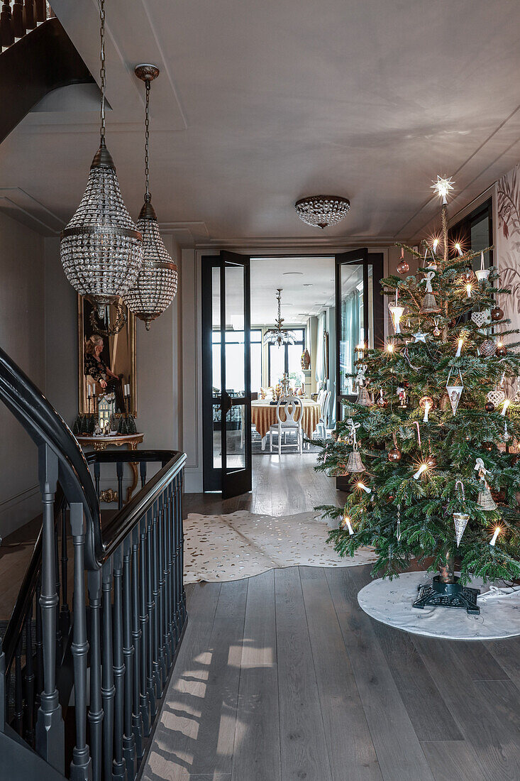 Beleuchteter Weihnachtsbaum in elegantem Vorraum mit Treppe