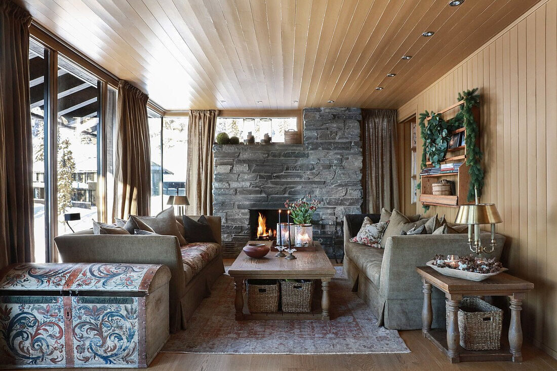Classic living room with fireplace and wood panelling in a cabine: painted wooden chest in foreground