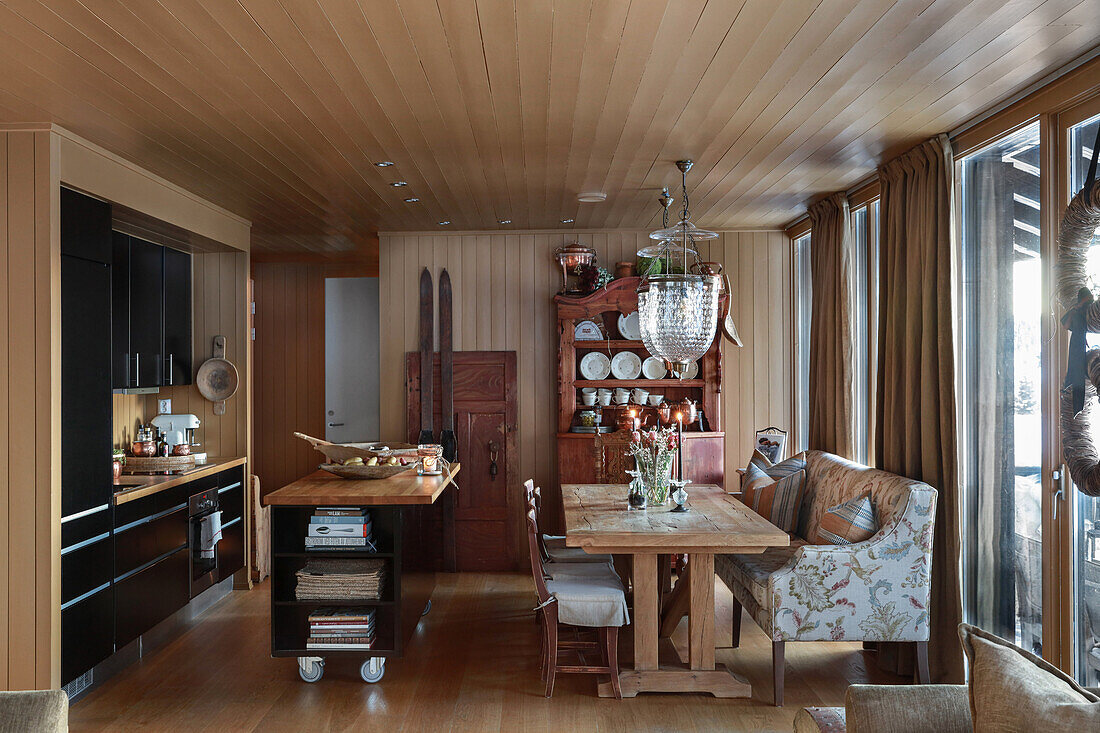 Schwarze Küche mit rollbarer Kücheninsel und Essbereich mit Polsterbank in einer Hütte