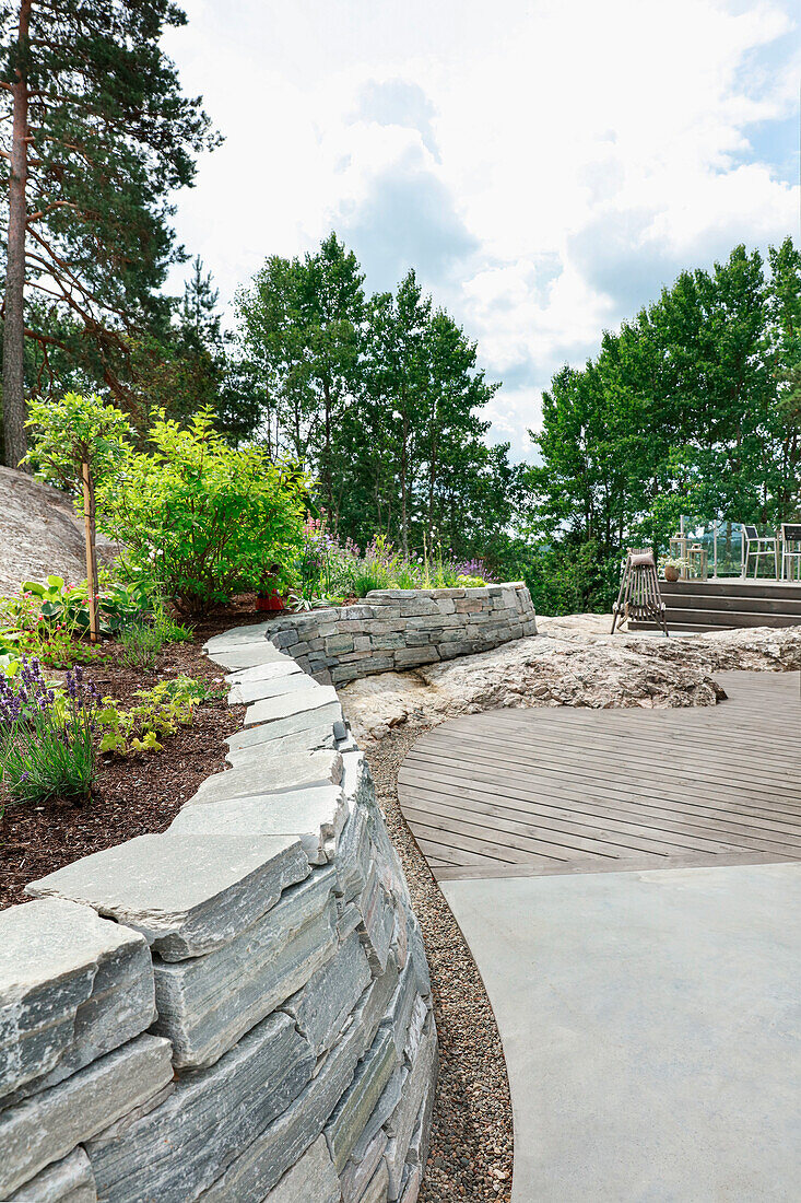 Flowerbed with stone wall on terrace surrounded by boulders