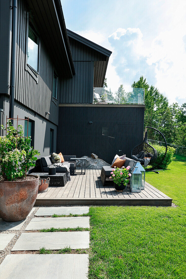 Terrace in grey adjoining house with modern lounge furniture in summer garden