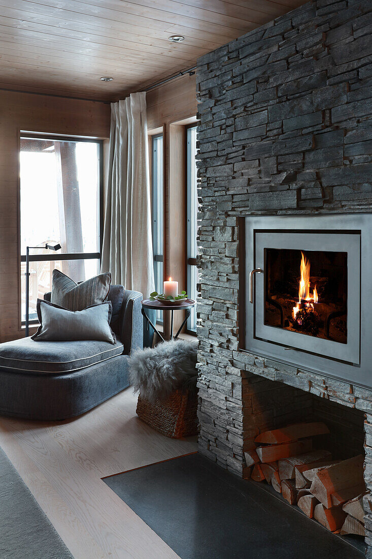 Kamin mit Natursteinwand in elegantem Wohnzimmer