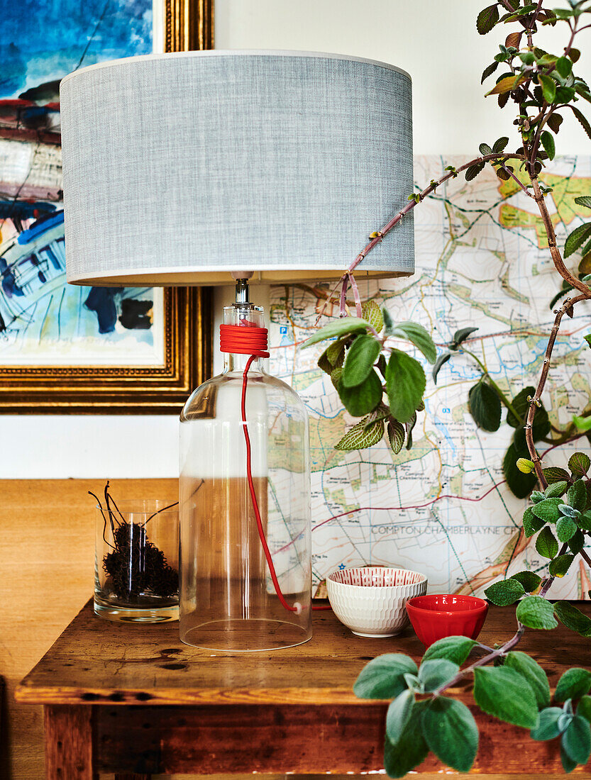 Wooden table with lamp and houseplant in front of street map on wall