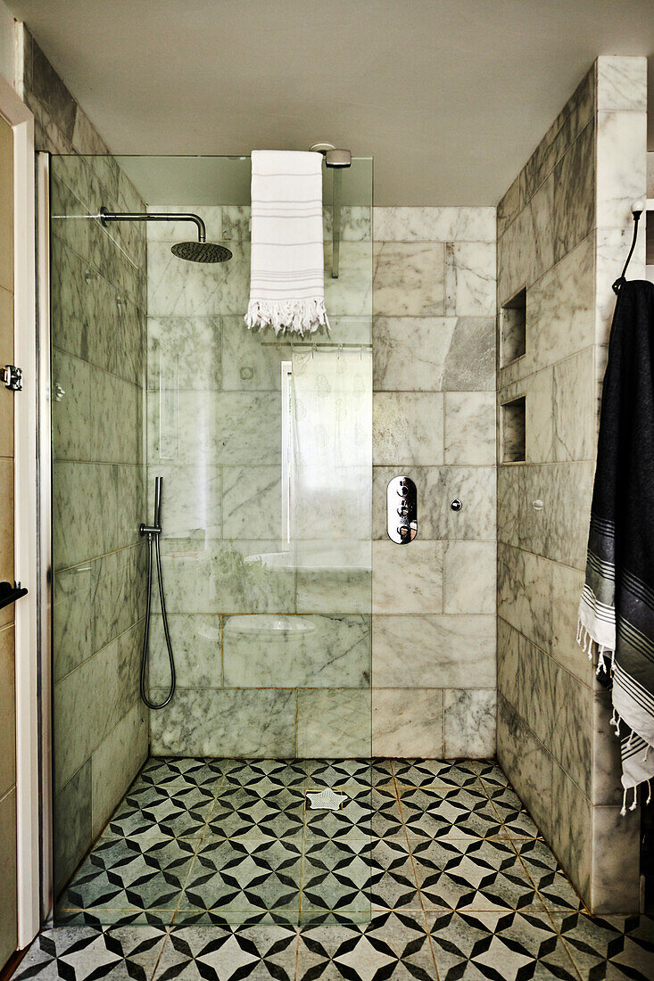 Shower area in bathroom with marble tiles