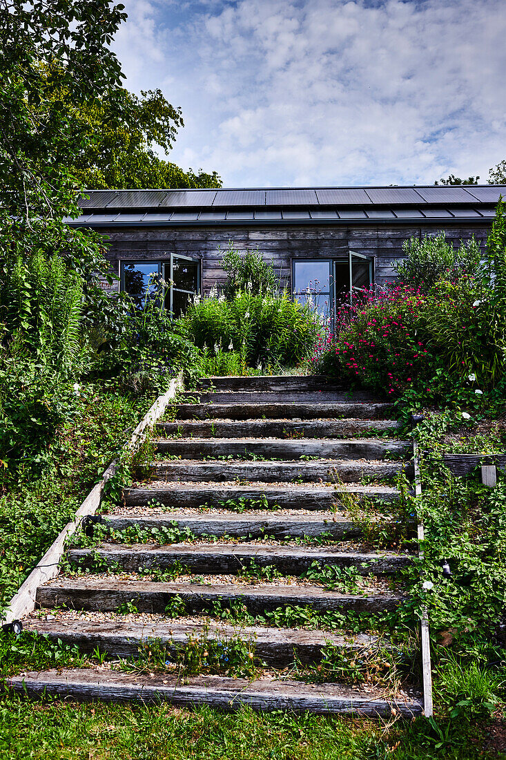 Treppenstufen führen in sommerlichem Garten zum Gartenhaus