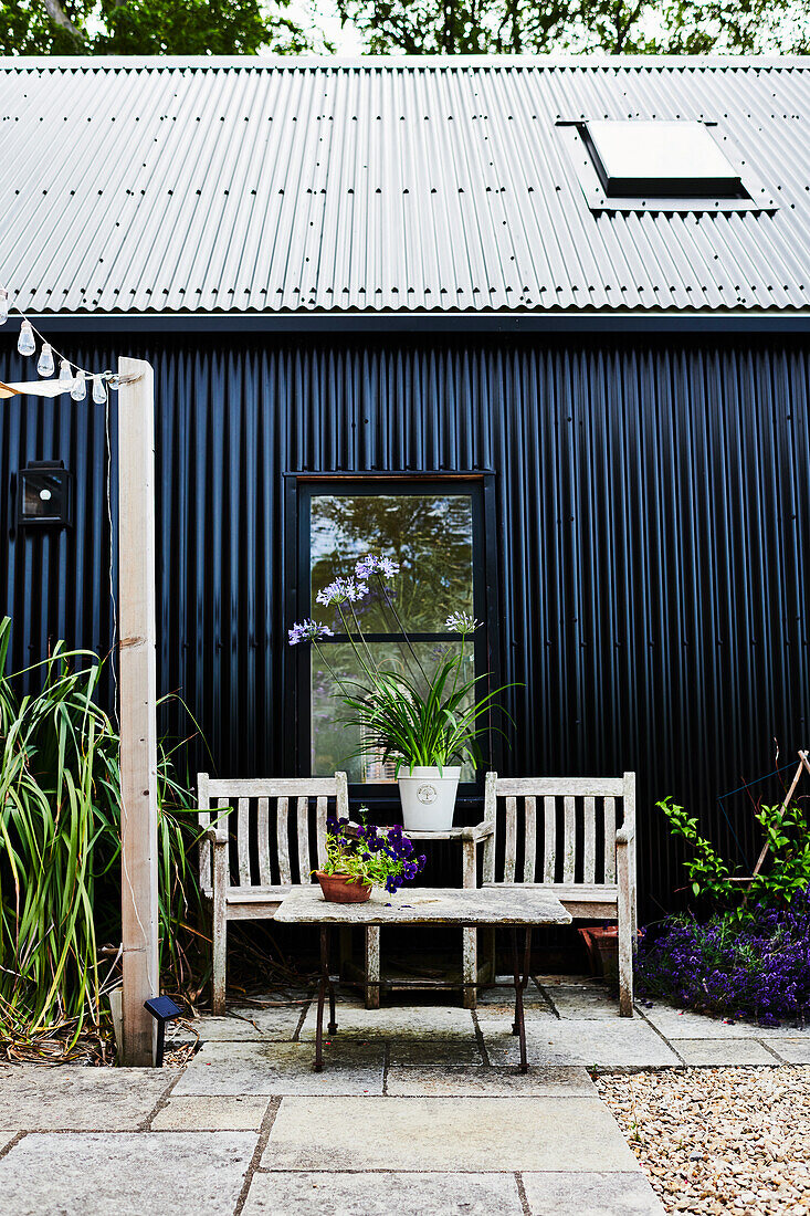 Seating area outside house clad in black corrugated iron