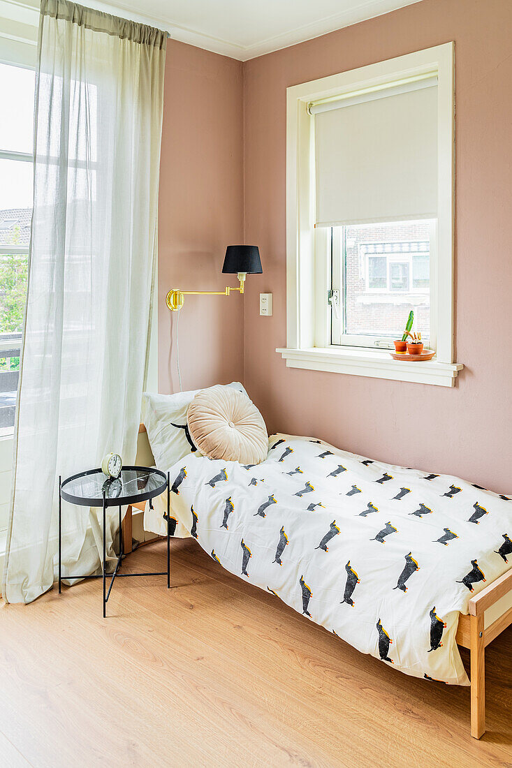 Bed linen with dachshund motif in guest room with dusky-pink walls