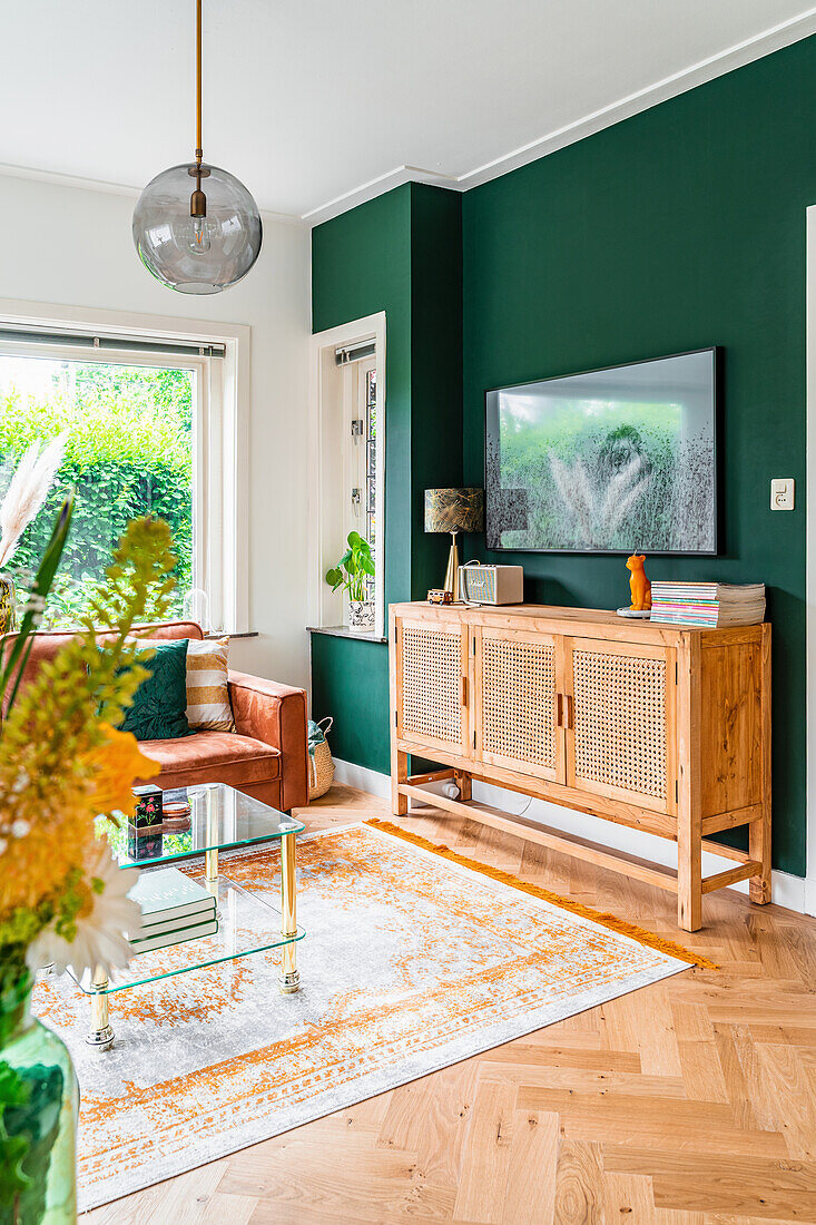 Sideboard vor dunkelgrüner Wand im Wohnzimmer in Naturtönen