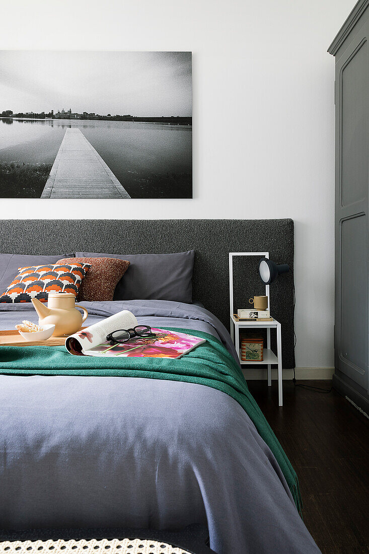 Doppelbett mit anthrazitfarbenem Betthaupt, darüber Landschaftsfoto