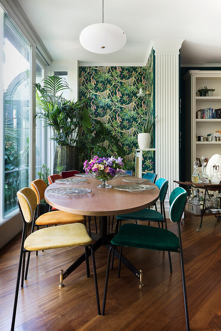 Oval dining table in room with jungle-patterned wallpaper