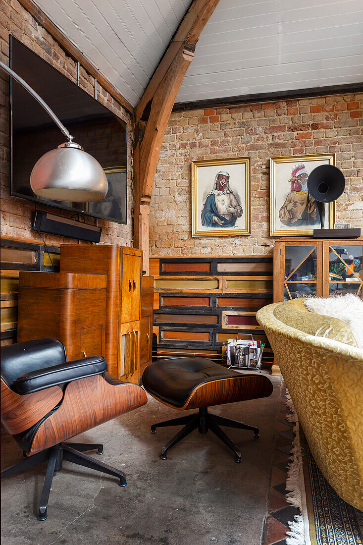 Designer chair with footstool in eclectic living room with an exposed brick wall