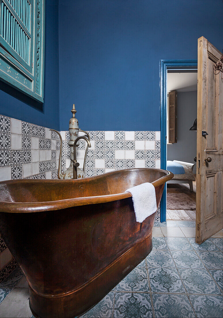 Freestanding bathtub in guest bathroom with blue wall and wall tiles