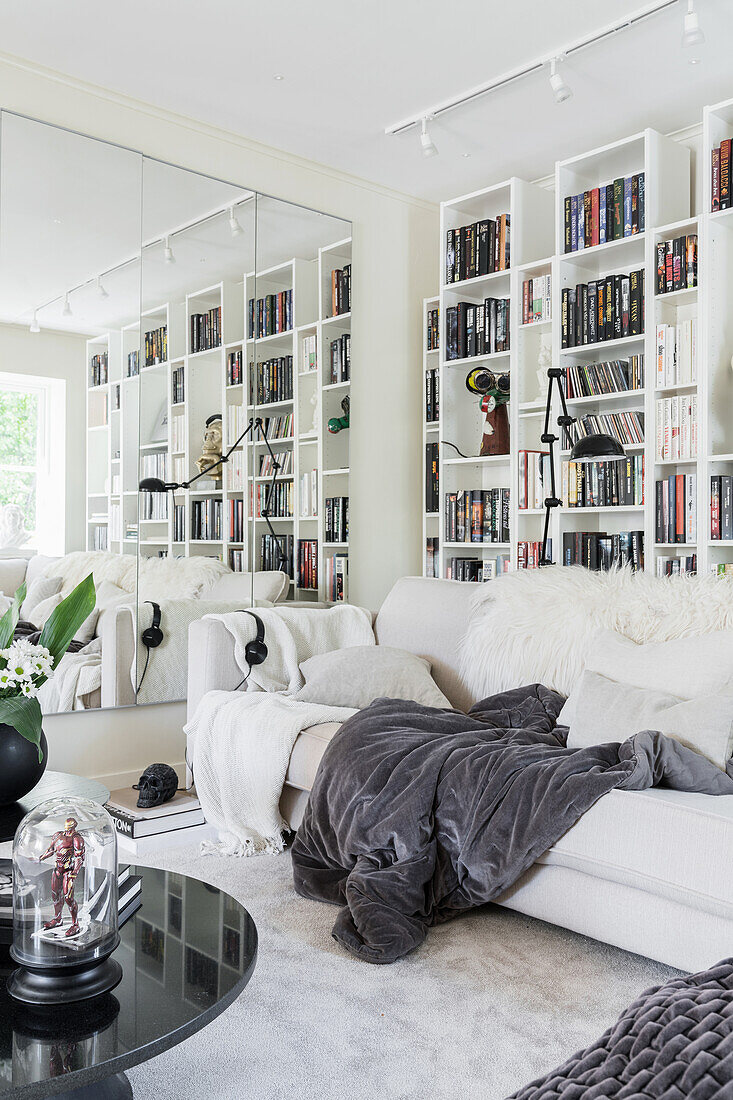 White living room with shelf wall, sofa and mirrorred wall