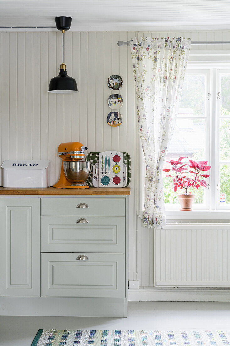White country-house kitchen with decorative wall plates on wooden panelling