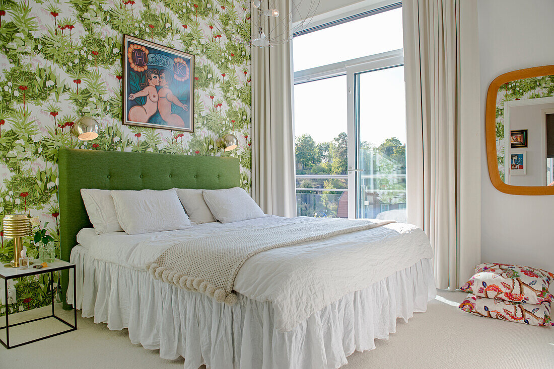 Doppelbett mit grünem Betthaupt im Schlafzimmer mit Blumentapete