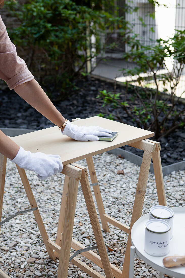 A wooden board on a wallpaper table being sanded down