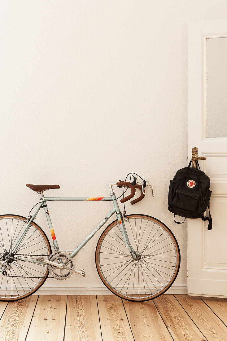 Fahrrad neben offener Tür mit Rucksack in Altbauwohnung