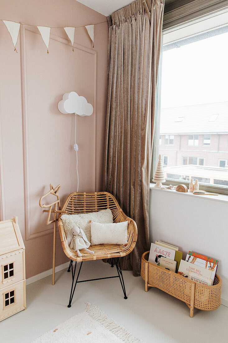 Rattansessel am Fenster mit bodenlangem Vorhang im Kinderzimmer