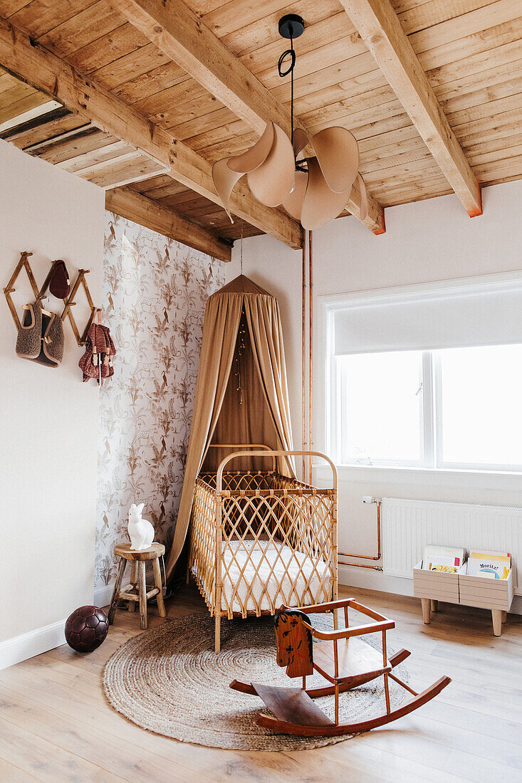 Cot with canopy in the nursery with high wooden ceiling