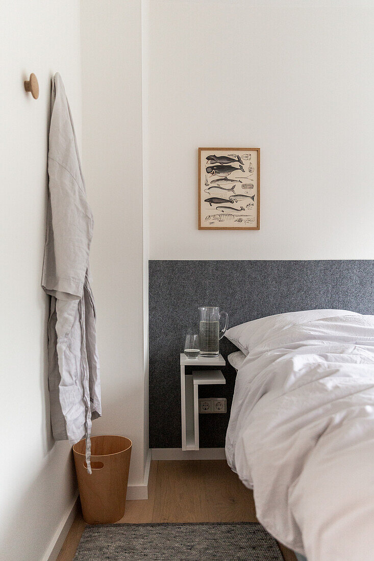 Bed with minimalist bedside table mounted on grey wall panel