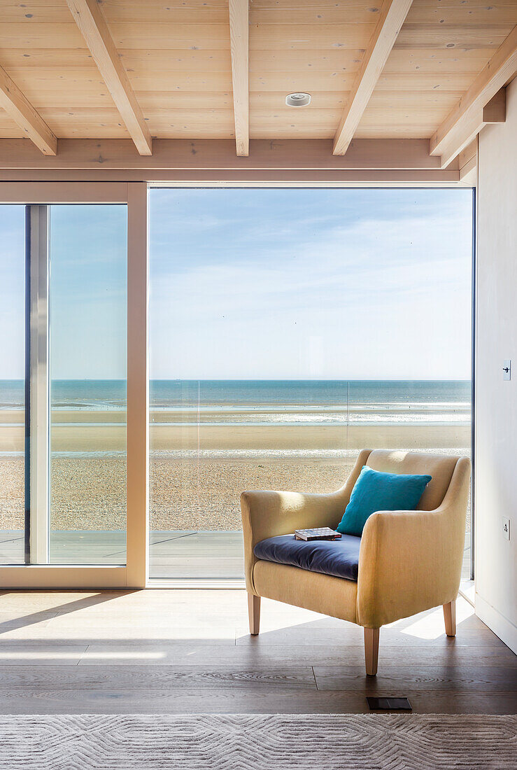 Yellow armchair next to open patio door with view of beach and sea