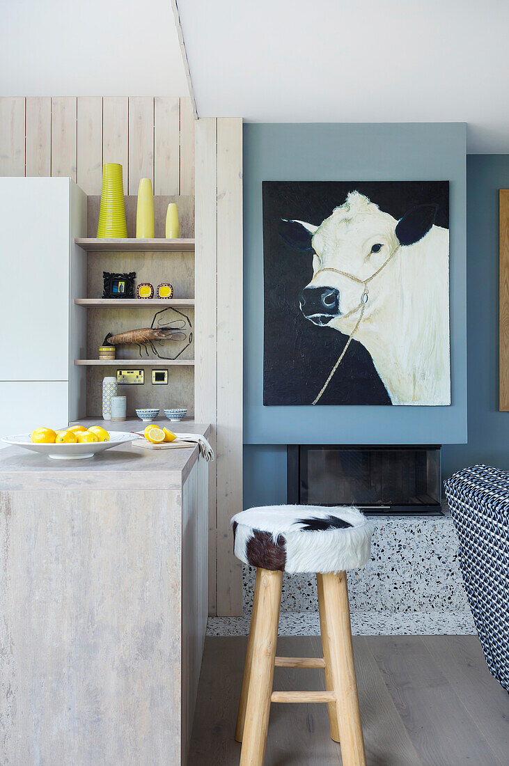 Cow portrait, kitchen counter and stool in open-plan interior