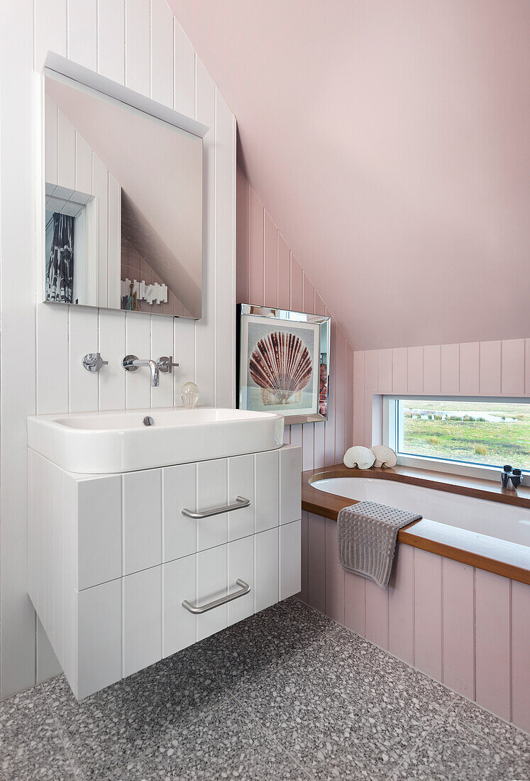 Washstand and bathtub in bathroom with pink wall