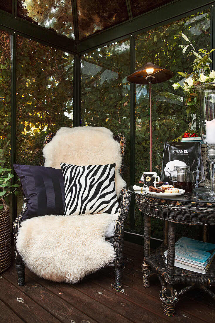 Runder Tisch, Sessel mit Schafsfell und Kissen in Animal-Print im Wintergarten
