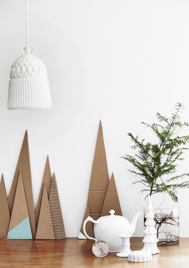 Decorative piles of paper, white lamp, white decoration and branch in glass jar